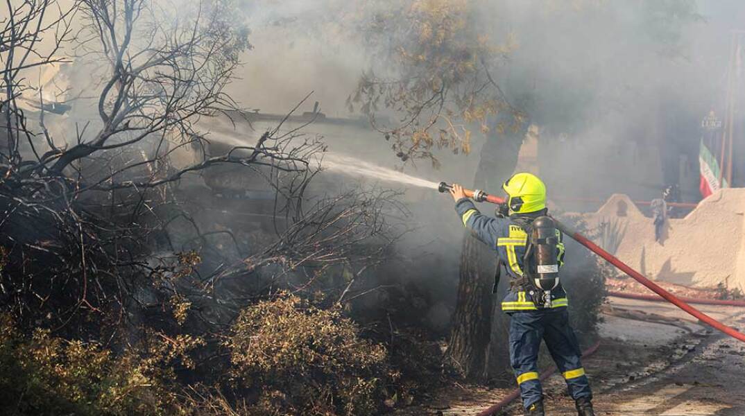 Πυροσβέστης ρίχνει νερό σε ενεργή εστία