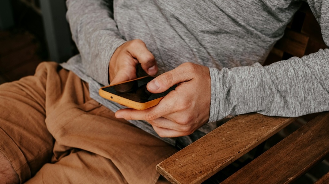 Άτομο κρατά κινητό και κάτι φαίνεται να πληκτρολογεί