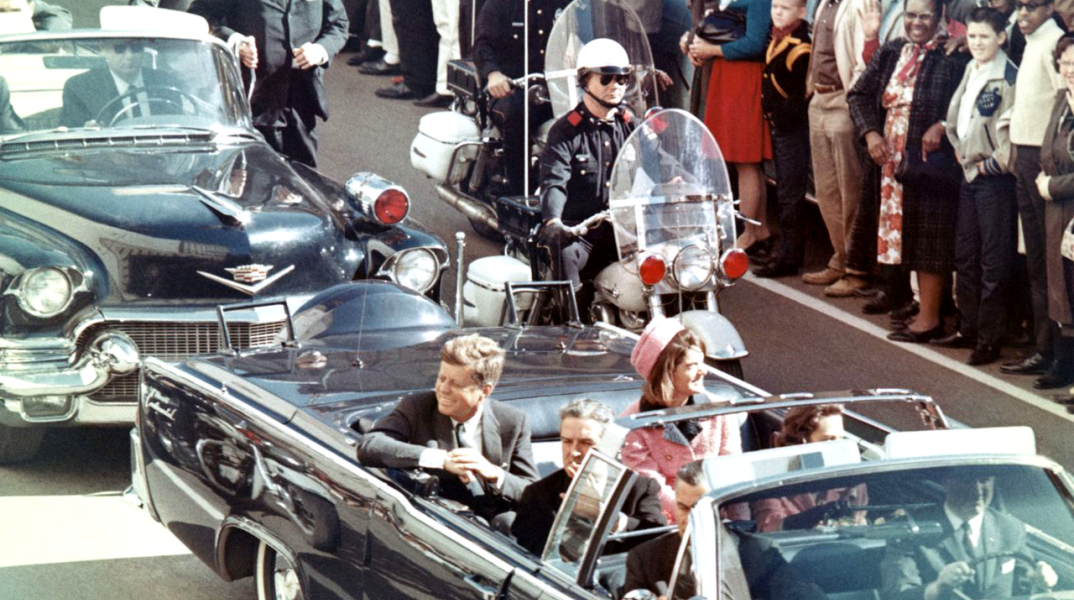 O JFK λίγο πριν δολοφονηθεί. Δίπλα του η Τζάκι, μπροστά του ο κυβερνήτης του Τέξας και στο πίσω αυτοκίνητο ο μυστικός πράκτορας Κλιντ Χιλ