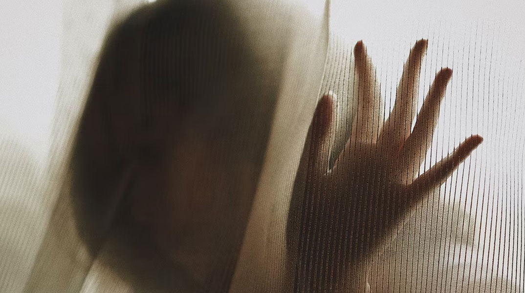 Γυναίκα με υψωμένα χέρια πίσω από κουρτίνα - Εικόνα που παραπέμπει σε βιασμό