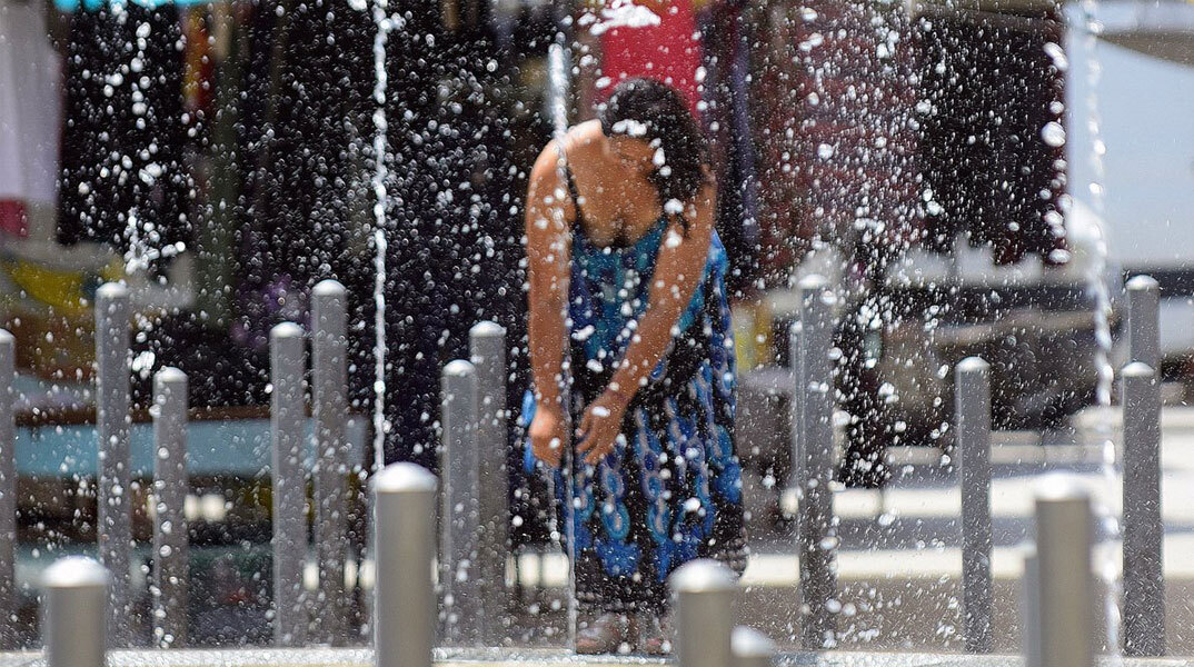 Γυναίκα δροσίζεται σε σιντριβάνι