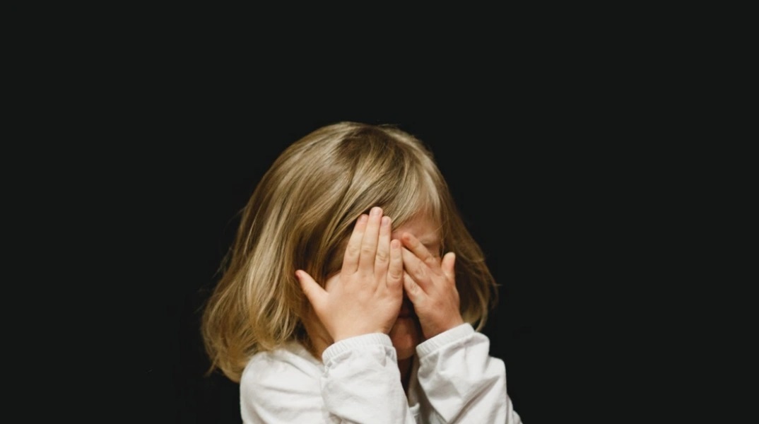 Παιδί κρύβει το πρόσωπό του - Εικόνα που παραπέμπει σε κακοποίηση