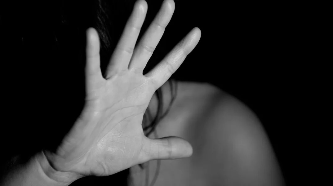 Γυναίκα προστατεύει με τα χέρια της το πρόσωπό της από τον κακοποιητή της
