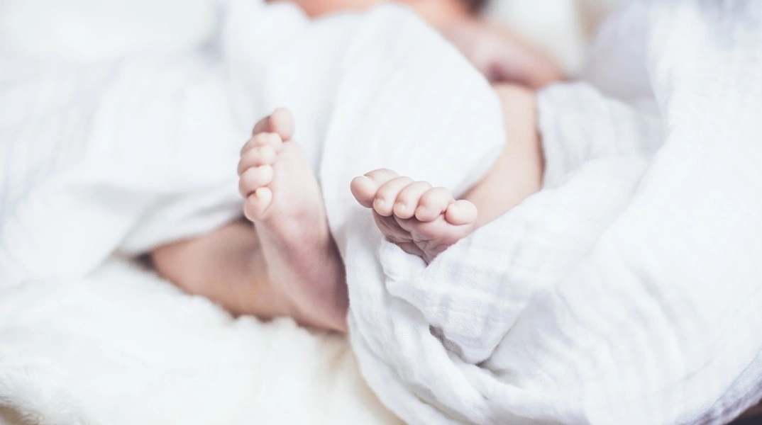 Πατουσάκια μωρού που είναι τυλιγμένα σε σεντόνι