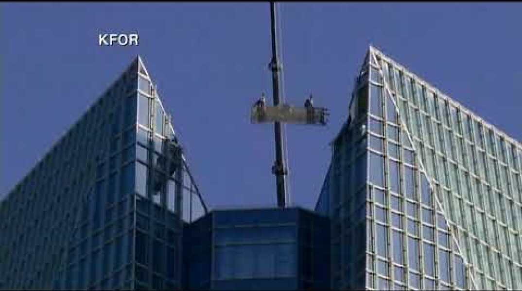 Window washers trapped in basket swinging at top of tower