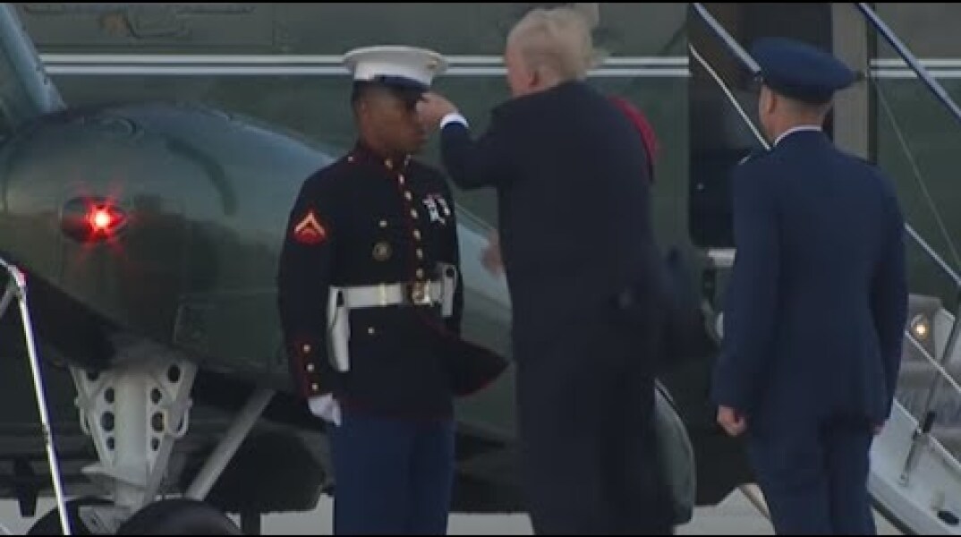 Trump struggles to retrieve marine hat blown off by the wind