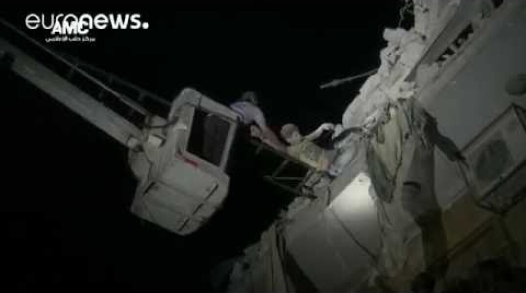Boy hangs from rubble of building destroyed by airstrike, Aleppo
