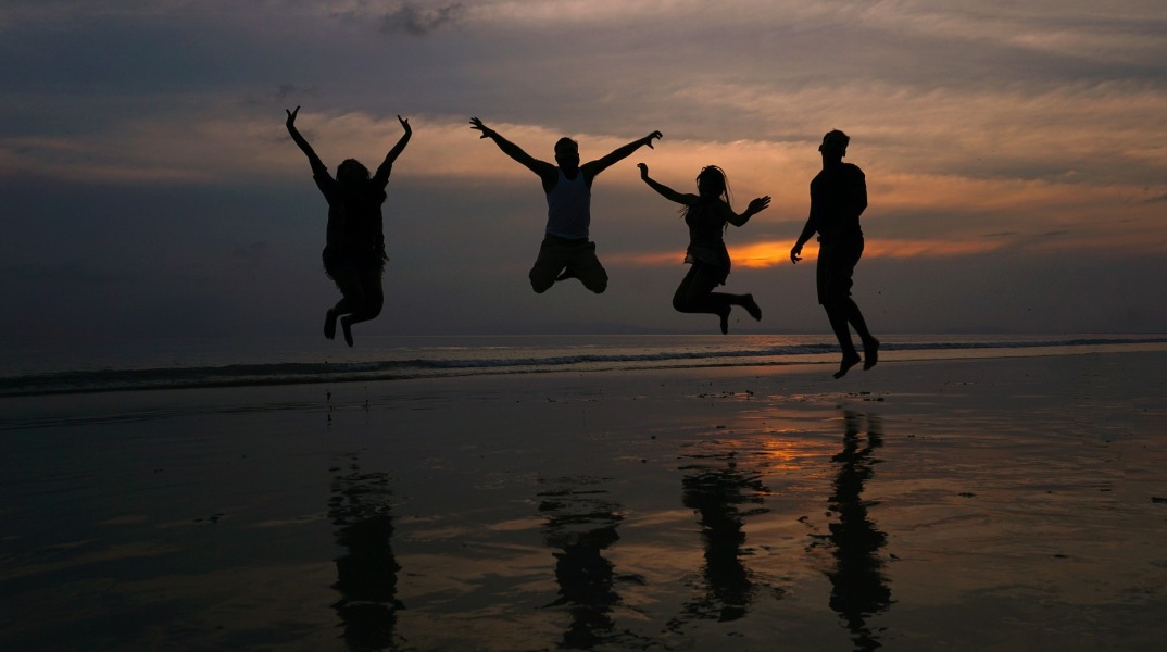 Άνθρωποι στην παραλία που χοροπηδούν