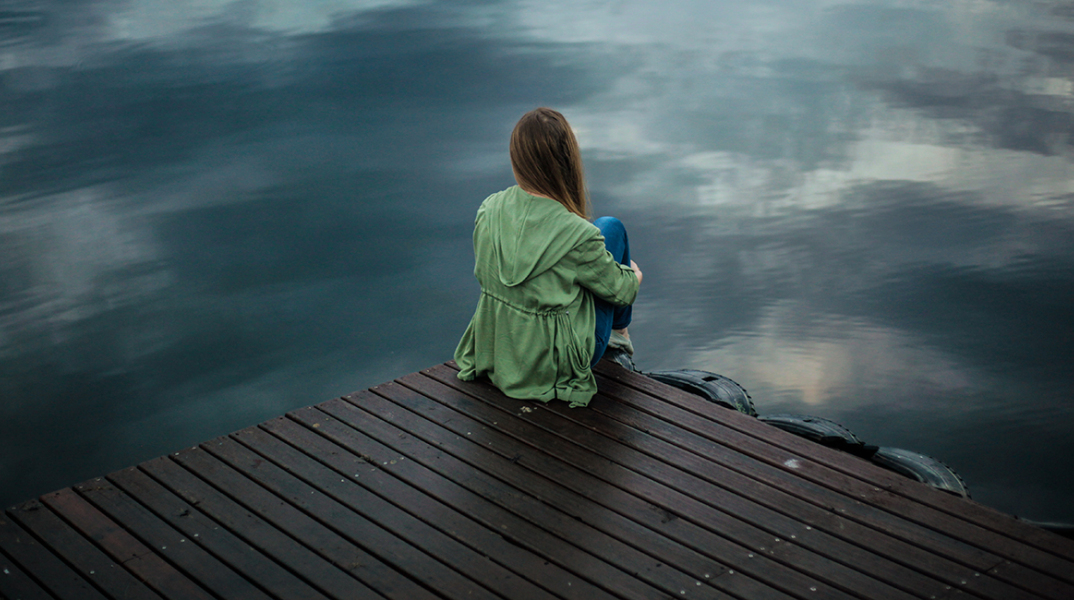 woman sitting on dock near body of water