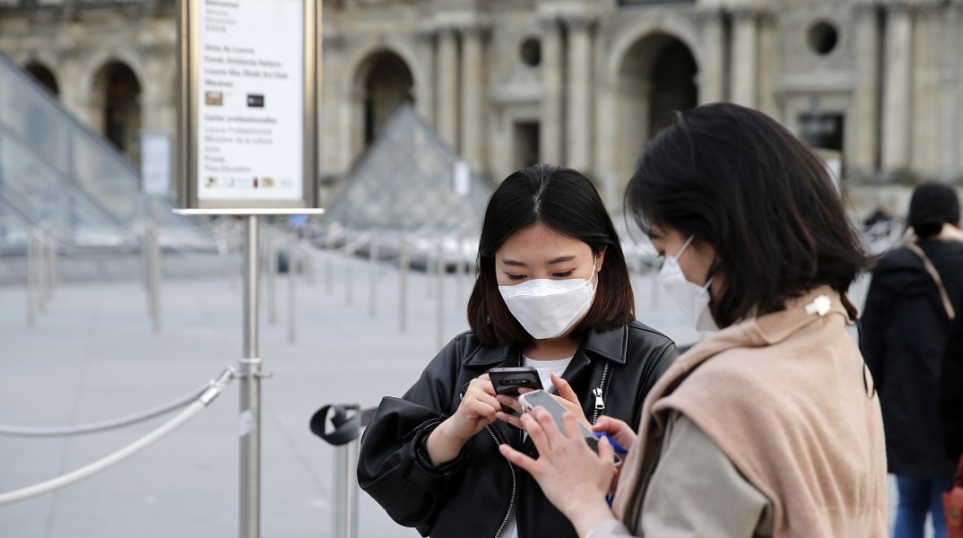 Κοπέλες με προστατευτικές μάσκες και κινητά