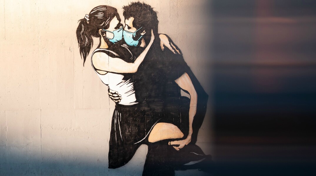 Stencil όπου απεικονίζεται αγόρι να φιλά κορίτσι με χειρουργικές μάσκες
