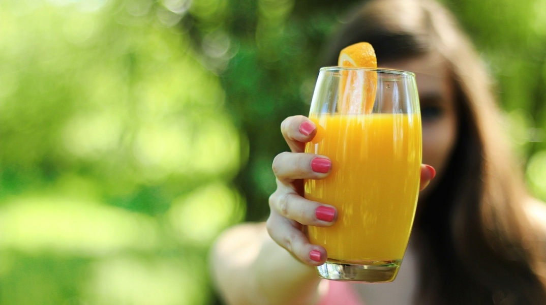 Κοπέλα που κρατάει ποτήρι με χυμό πορτοκάλι