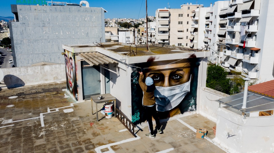 Ο 16ΧΡΟΝΟΣ S.F. ΖΩΓΡΑΦΙΖΕΙ ΓΚΡΑΦΙΤΙ ΜΕ ΘΕΜΑ ΕΜΠΝΕΥΣΜΕΝΟ ΑΠΟ ΤΗΝ ΠΡΟΣΤΑΣΙΑ ΑΠΟ ΤΟΝ ΚΟΡΩΝΟΙΟ ΣΕ ΤΑΡΑΤΣΑ ΤΗΣ ΟΔΟΥ ΒΟΥΛΙΑΓΜΕΝΗΣ