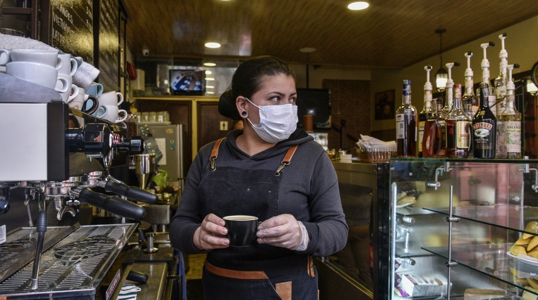 Γυναίκα με προστατευτική μάσκα και γάντια σε καφέ