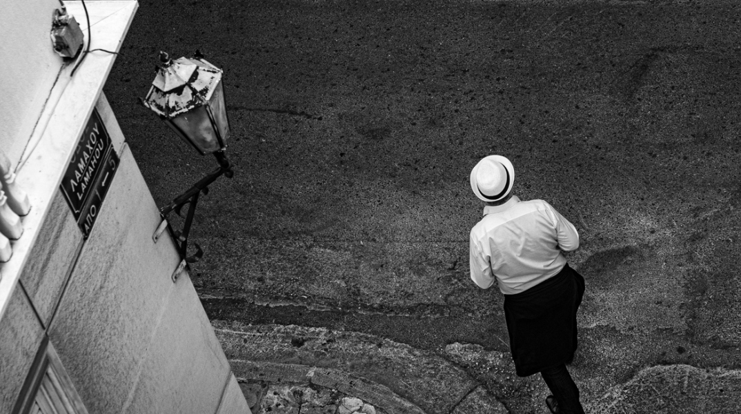 Φωτογραφία με έναν άνθρωπο με καπέλο στον άδειο δρόμο του Συντάγματος