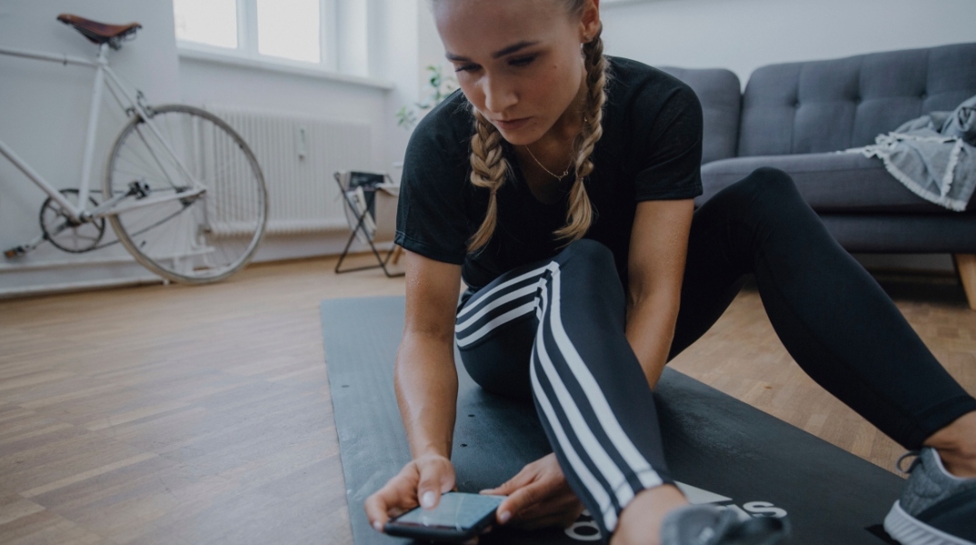 Κορίτσι γυμνάζεται στο σπίτι με τη βοήθεια του app της adidas