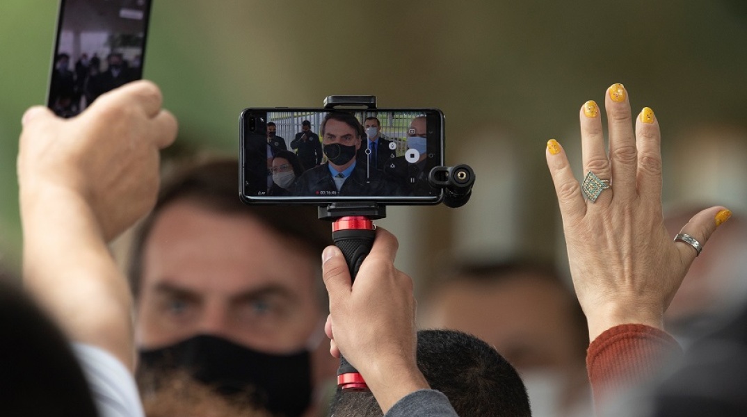 Ο Μπολσονάρου με μάσκα μέσα από την οθόνη ενός κινητού