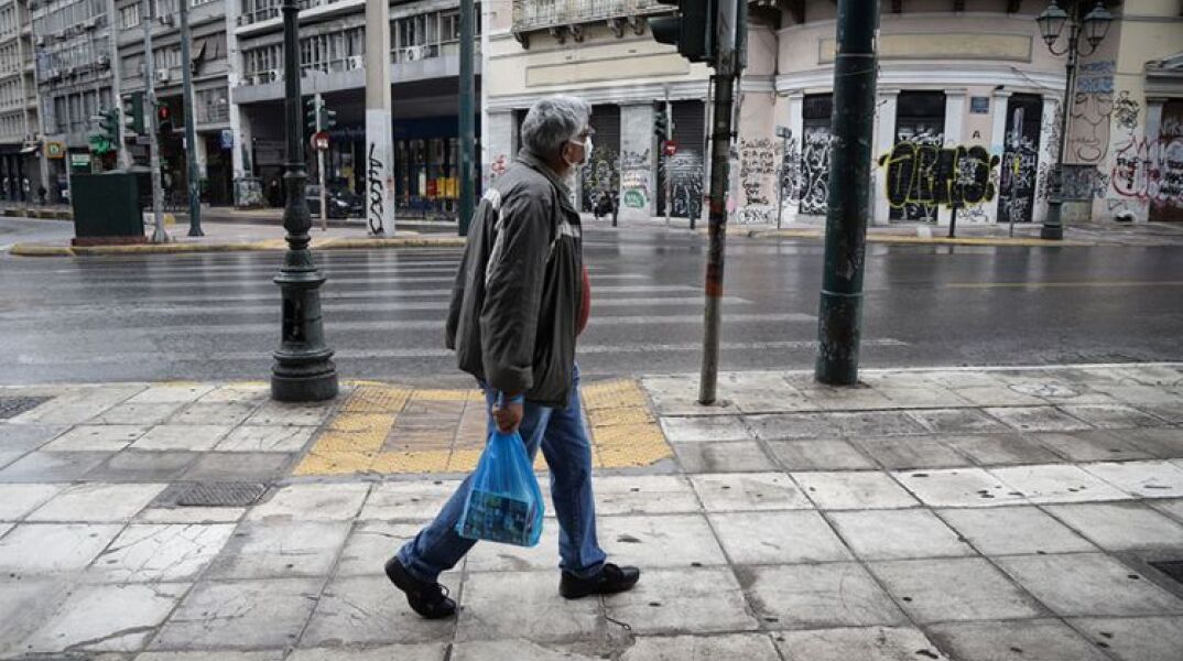Άνδρας στο βροχερό κέντρο της Αθήνας με μάσκα