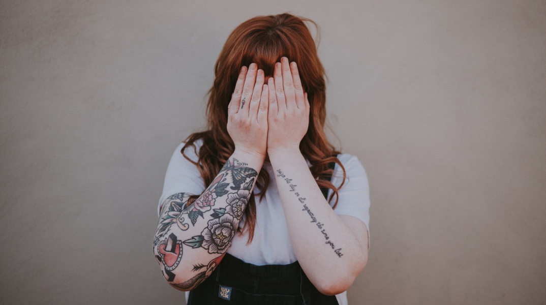Γυναίκα που κρύβει με τα χέρια της το πρόσωπό της