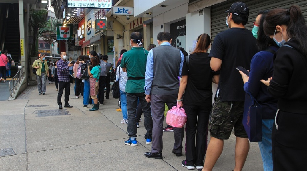 Άνθρωποι περιμένουν στην ουρά φορώντας μάσκες
