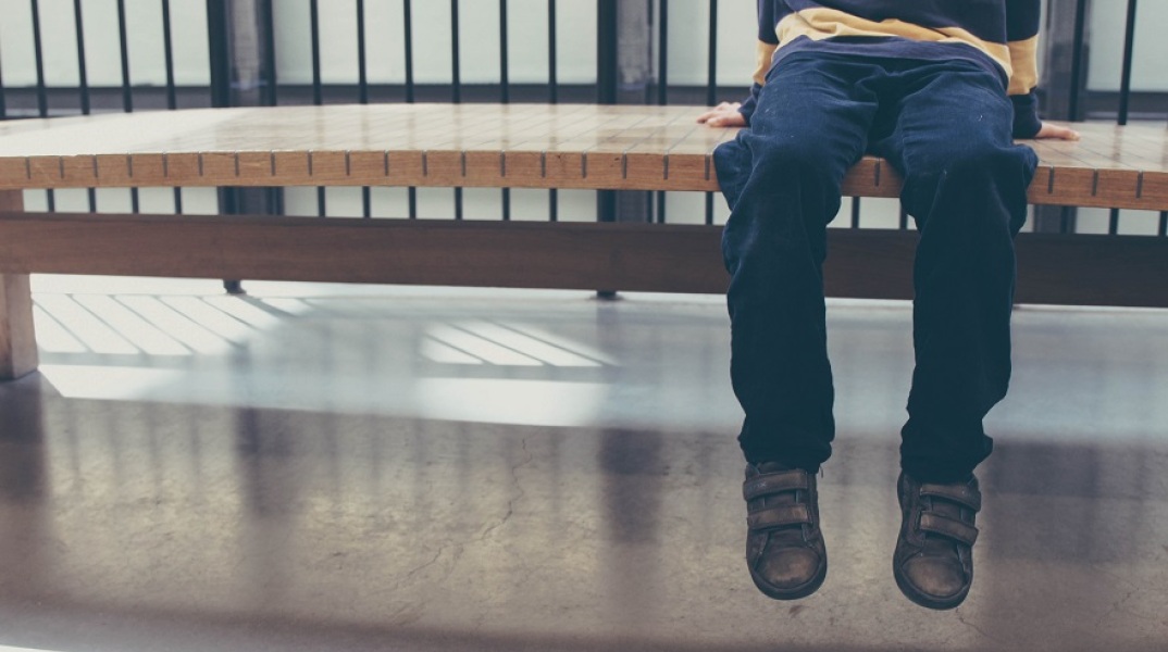 Παιδί κάθεται σε παγκάκι