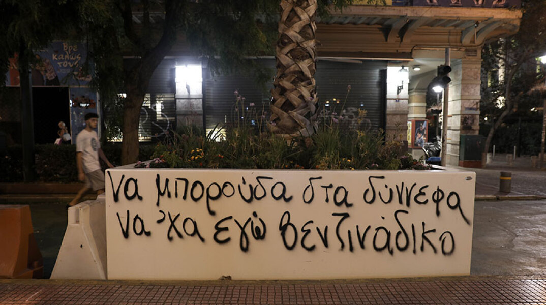 Συνθήματα στις ζαρντινιέρες με τους φοίνικες στην οδό Πανεπιστημίου κατά μήκος του «Μεγάλου Περιπάτου της Αθήνας»