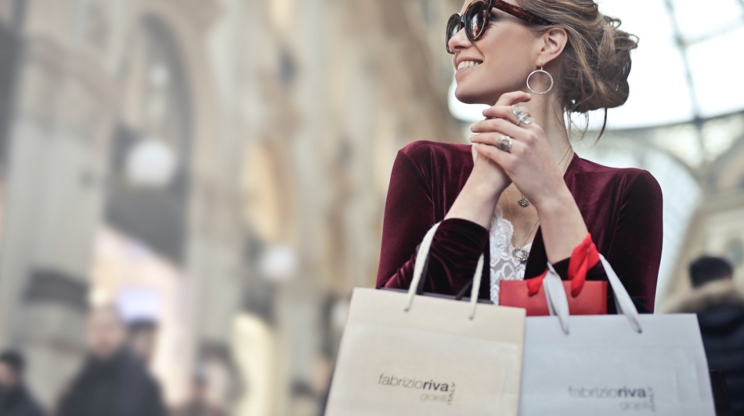 Γυναίκα με γυαλιά ηλίου και σακούλες μαγαζιών στα χέρια