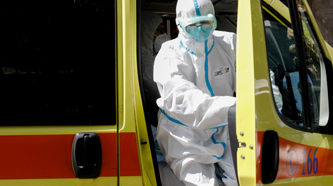 Μέλος του πληρώματος σε ασθενοφόρο του ΕΚΑΒ με προστατευτική στολή για τον κορωνοϊό