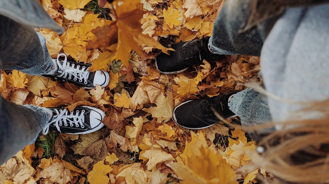 Κορίτσια στέκονται όρθια πάνω σε κιτρινισμένα, πεσμένα φύλλα δέντρων
