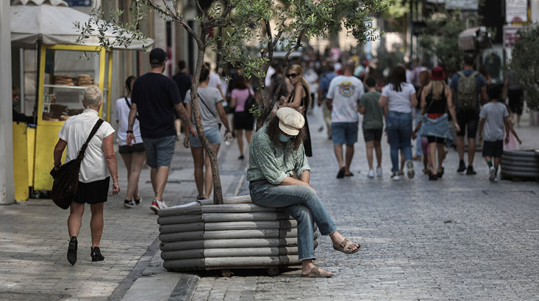 Άνδρας με μάσκα για τον κορωνοϊό κάθεται σε παρτέρι στο κέντρο της Αθήνας