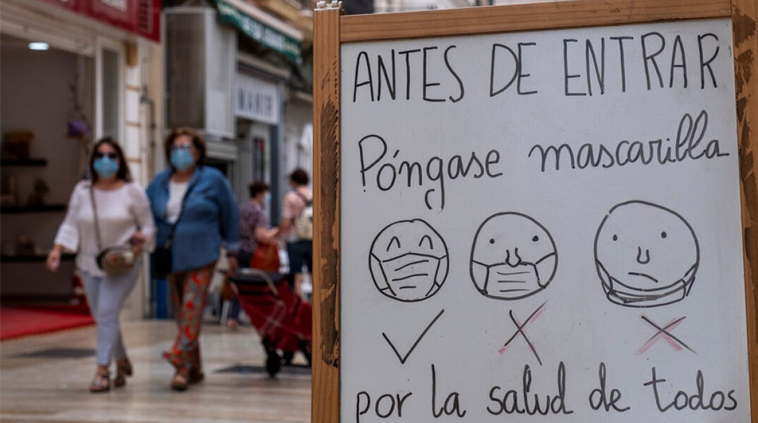 «Πριν μπείτε, φορέστε μάσκα για την ασφάλεια όλων μας» το μήνυμα στην είσοδο καταστήματος στην Ισπανία