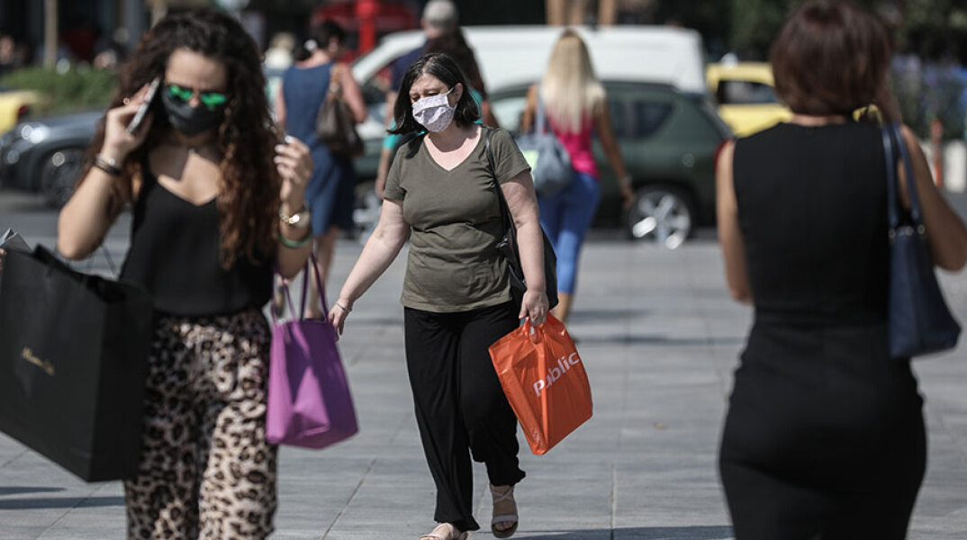 Πολίτες με μάσκα για τον κορωνοϊό περπατούν στο κέντρο της Αθήνας