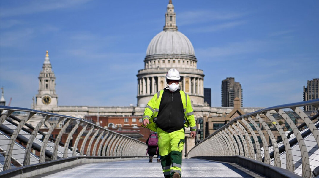 Μεγάλη Βρετανία: Εργάτης με μάσκα για τον κορωνοϊό διασχίζει τη Millennium Bridge στο Λονδίνο