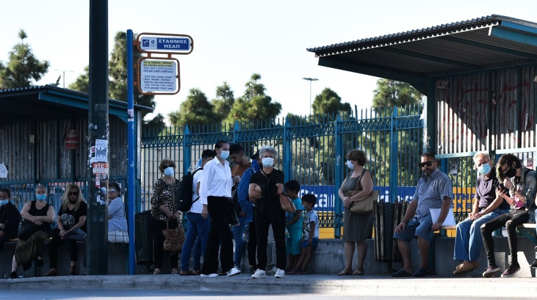 Άνθρωποι με μάσκα σε στάση λεωφορείου