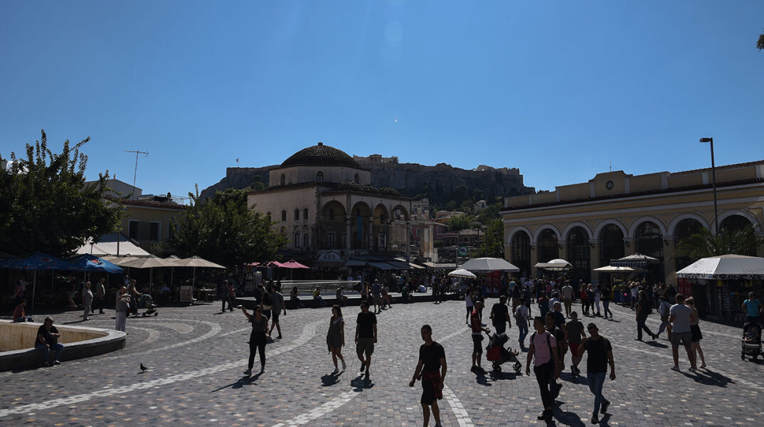 Κόσμος περπατά στην πλατεία στο Μοναστηράκι, με κάποιους να φορούν μάσκα για τον κορωνοϊό