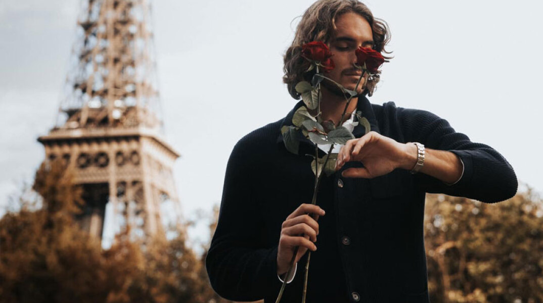 Ο Στέφανος Τσιτσιπάς κοιτά το ρολόι του, κρατώντας ένα κόκκινο τριαντάφυλλο, με φόντο τον Πύργο του Άιφελ στο Παρίσι