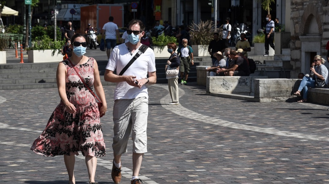Πολίτες περπατούν στο δρόμο φορώντας μάσκα