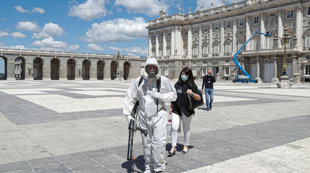 Κορωνοϊός στην Ισπανία: Υπάλληλος με προστατευτική μάσκα για τον κορωνοϊό απολυμαίνει ανοικτό χώρο