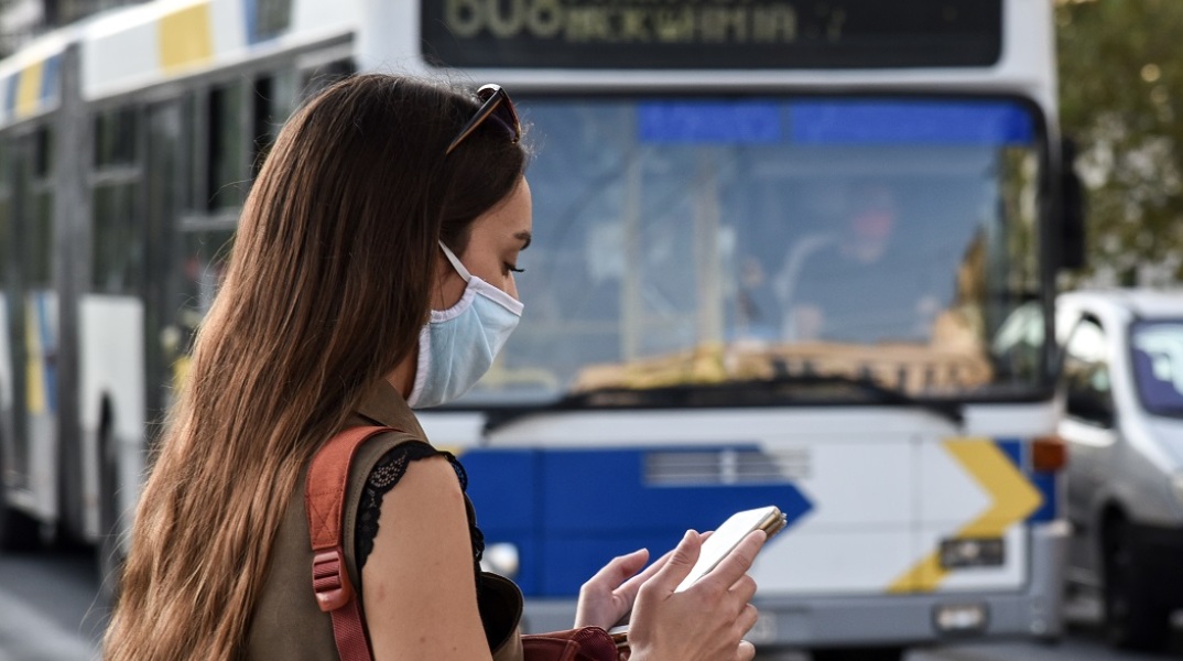 Κοπέλα με μάσκα σε στάση λεωφορείων