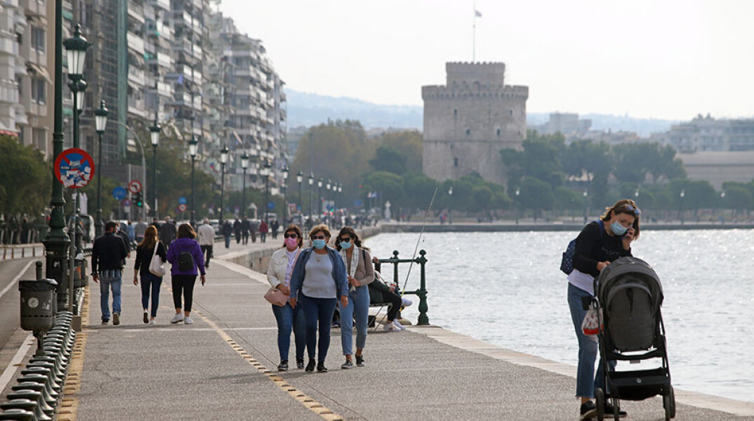 Πολίτες στη Θεσσαλονίκη περπατούν με μάσκα για τον κορωνοϊό