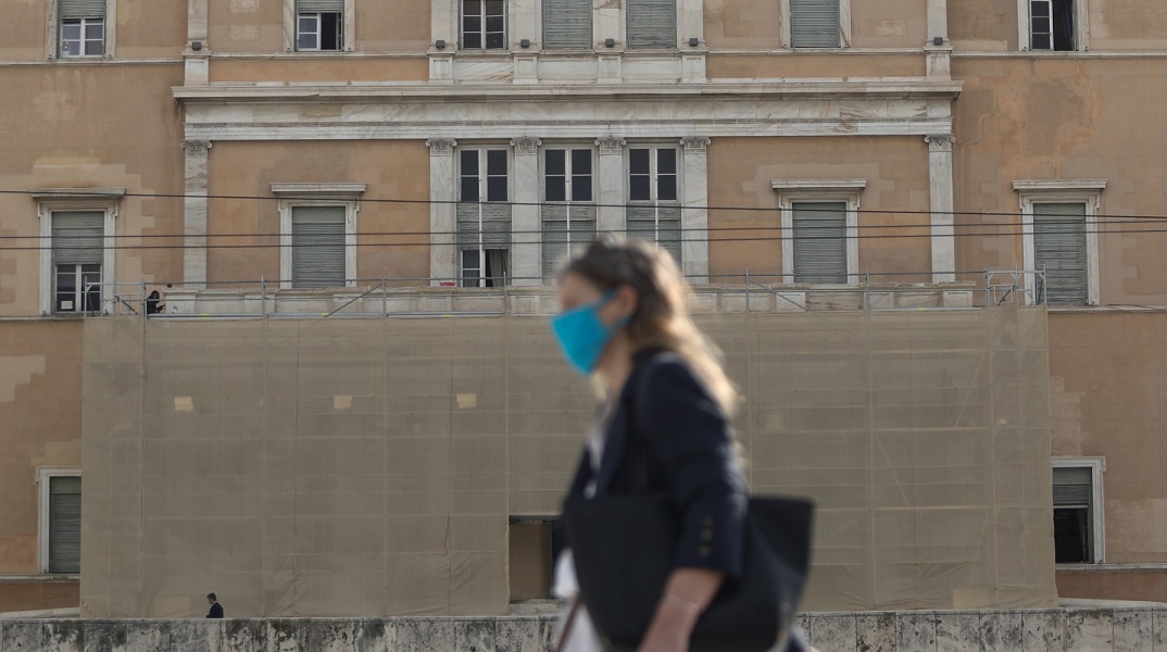 Γυναίκα που φορά χειρουργική μάσκα έξω από την Βουλή