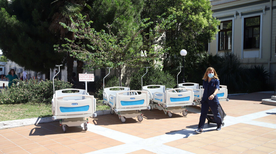 Φορεία στον προαύλιο χώρο νοσοκομείου και γυναικα με ιατρική στολή και μάσκα