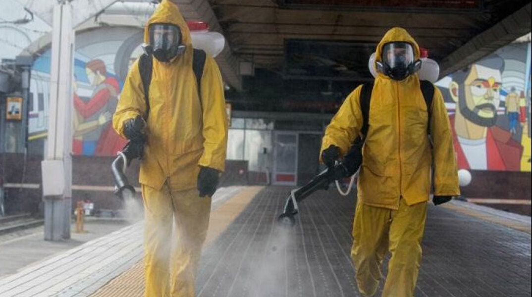 Άνδρες με προστατευτικές στολές για τον κορωνοϊό στη Μόσχα