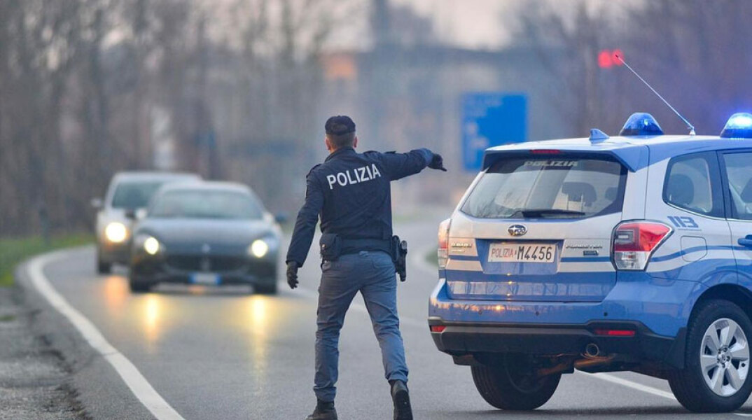 Ιταλία - Κορωνοϊός: Αστυνομικός κάνει σήμα σε οδηγό αυτοκινήτου να σταματήσει για έλεγχο