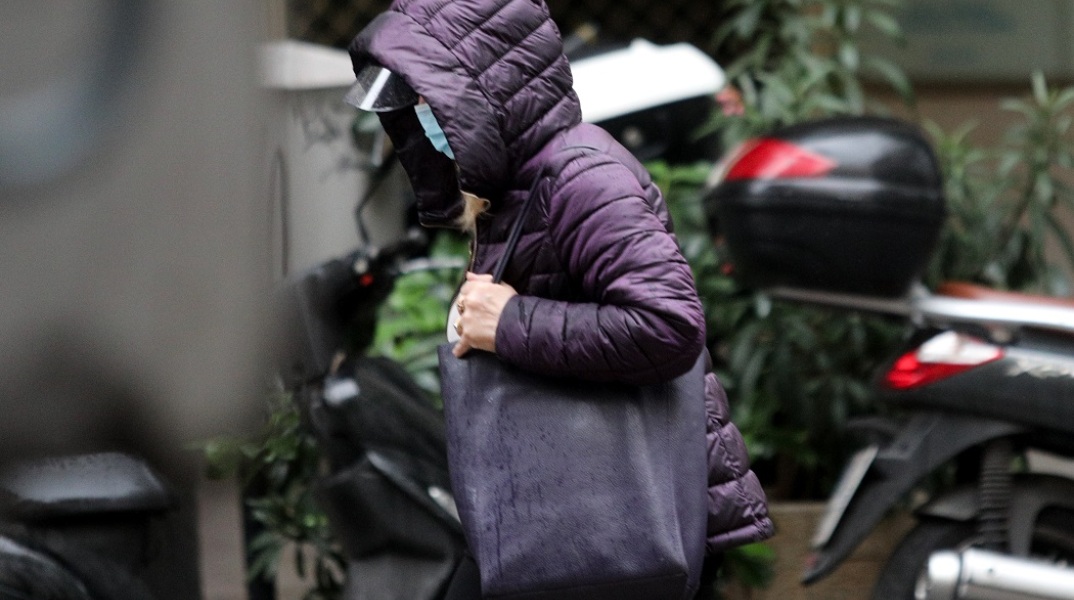 Γυναίκα με μπουφάν και μάσκα για τον κορωνοϊό στο δρόμο