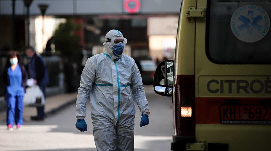 Τραυματιοφορέας με προστατευτική στολή για τον κορωνοϊό δίπλα σε ασθενοφόρο του ΕΚΑΒ