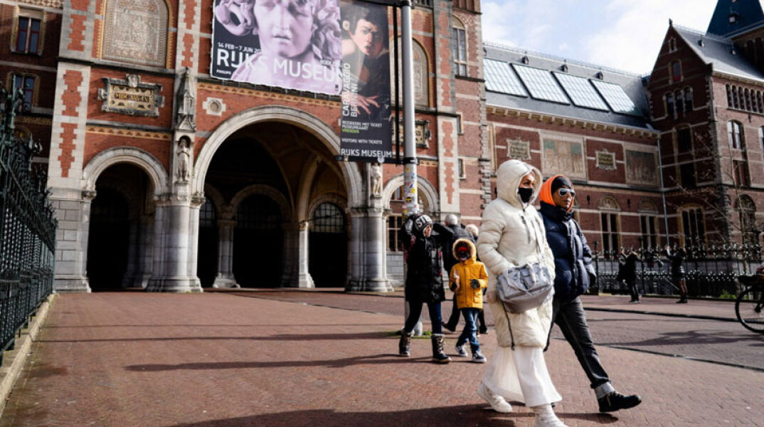 Πολίτες με μάσκα για τον κορωνοϊό περπατούν στο Άμστερνταμ