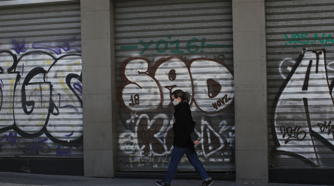 Γυναίκα με μάσκα για τον κορωνοϊό μπροστά από κλειστό κατάστημα στο κέντρο της Αθήνας