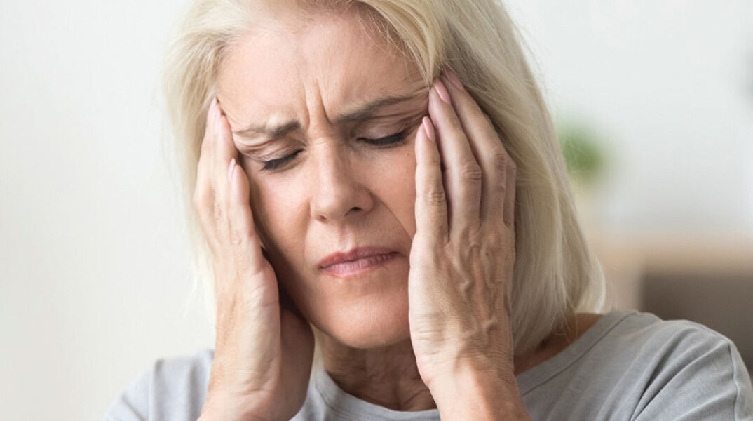 Ηλικιωμένη γυναίκα πιάνει το κεφάλι της με τα χέρια