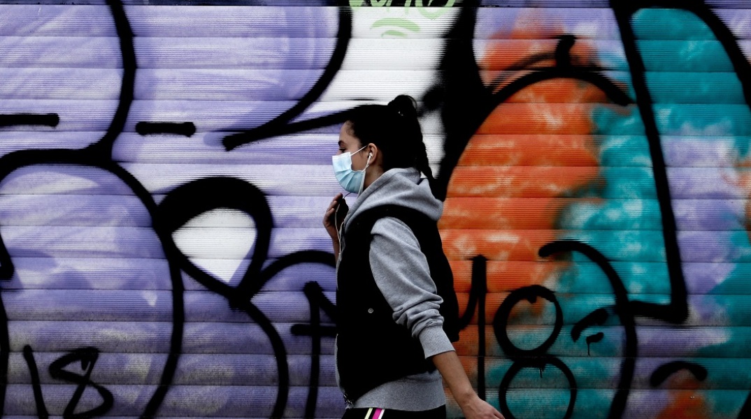 Στιγμιότυπο από το lockdown - Κοπέλα περπατά φορώντας μάσκα